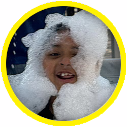 A child smiles with their face covered in soap bubbles, framed by a yellow circle.