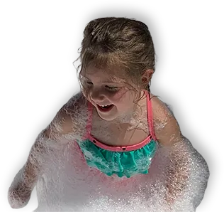 inset-girl-masked A young girl in a green and pink swimsuit smiles and plays, covered in bubbles, against a black background.